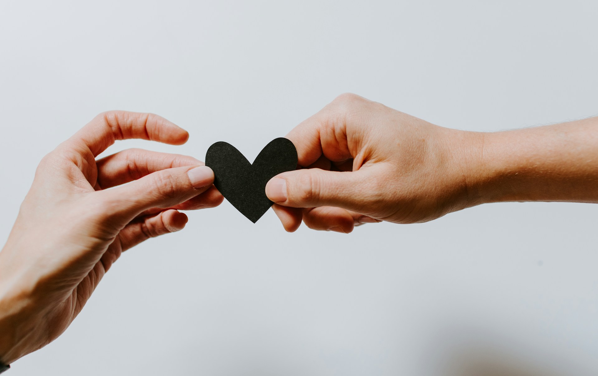 Two hands holding a black paper hearth, blurry background